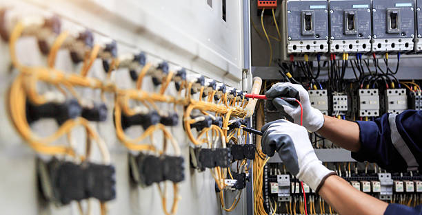 Elektriker mäter spänning med multimeter i elskåp