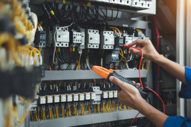 Elektriker mäter med tångamperemeter i en industriell elcentral